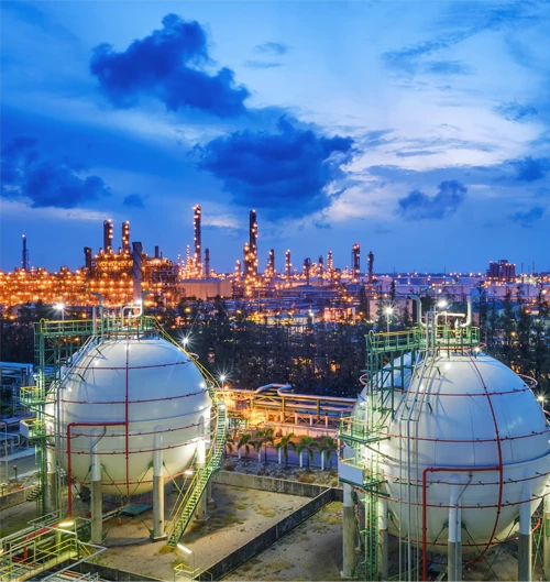 A petrochemical plant at dusk with large spherical storage tanks in the foreground